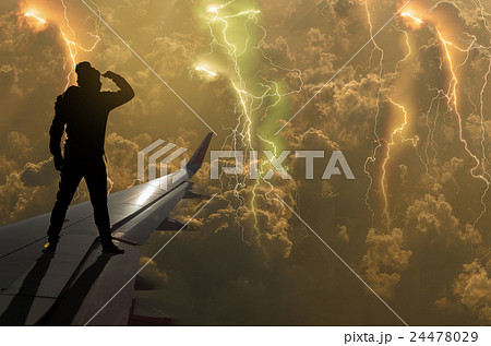 silhouette of man who looking the thunder lightnings over the clouds and storm on airplane wing, Challenge business concept 24478029