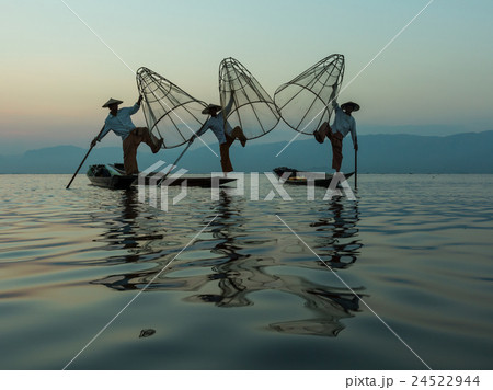 Three fishermen catches fish on the boat. 24522944