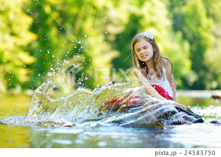 Cute little girl having fun by a river on warm summer day 24583750