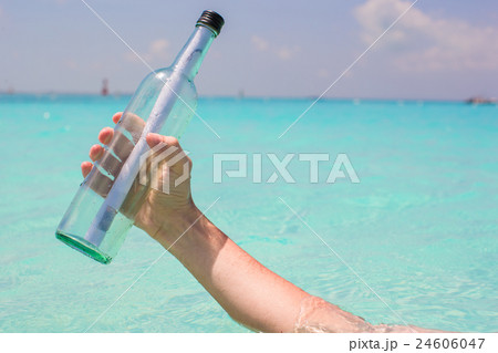 Bottle with a message in the hand background blue 24606047