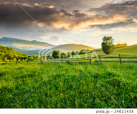 fence on hillside meadow in mountain at sunrise 24621438