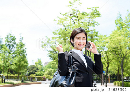 綺麗な街路樹を背景に電話しながらガッツポーズする若い会社員の女性 ビジネスウーマンの写真素材 24623592 Pixta