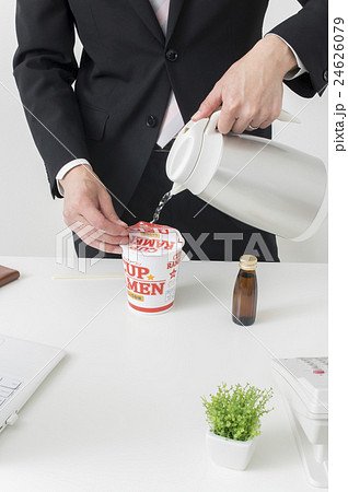 カップラーメンにお湯を注ぐビジネスマンの写真素材