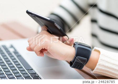 Woman connecting smart watch and cellphone Woman connecting smart watch and cellphone 24628785