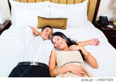 Asian couple lying on bed in hotel room 24687569