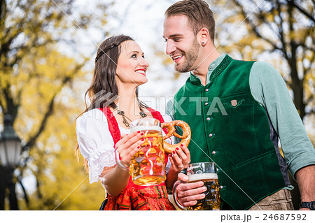 Couple in Tracht having Pretzel and Bier 24687592