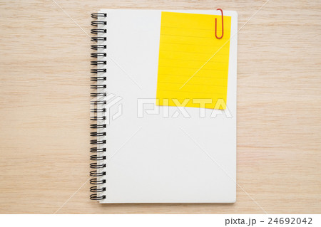 Yellow memo note clip on notebook on wooden table 24692042