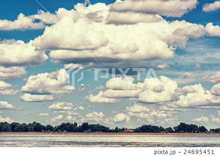 Waterfront with trees and house and blue sky 24695451