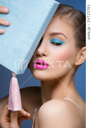 Girl with bright makeup holding book 24715761