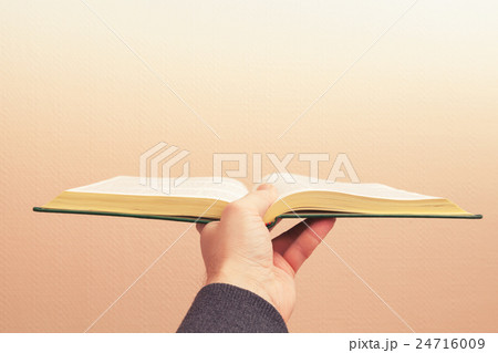 Open vintage book in male hand, old style photo 24716009