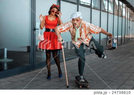 Old man ridiculously rides a skateboard. 24736610