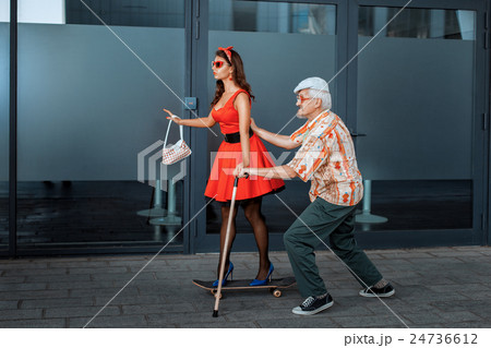 Old man teaches to ride a skateboard young girl. 24736612