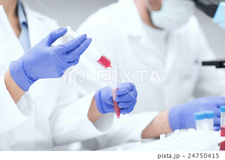 close up of scientists hands with test tube in lab 24750415