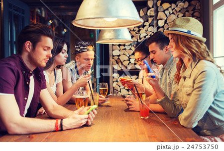 friends with smartphones and drinks at bar friends with smartphones and drinks at bar 24753750