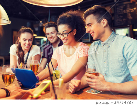 happy friends with tablet pc and drinks at bar happy friends with tablet pc and drinks at bar 24754737