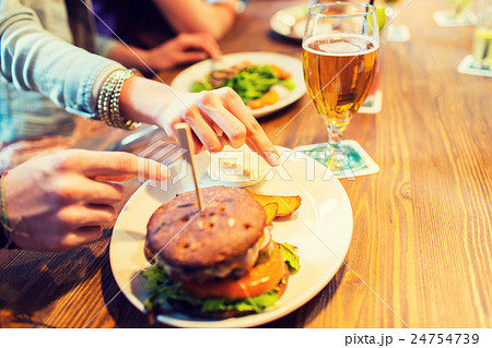 close up of friends hands sharing burger at bar 24754739