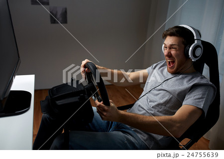 man playing car racing video game at home man playing car racing video game at home 24755639