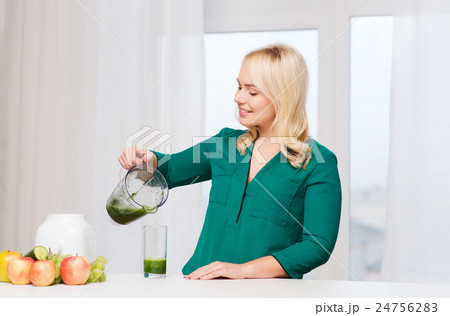happy woman with blender jug pouring juice at home happy woman with blender jug pouring juice at home 24756283