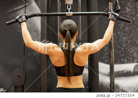 woman flexing muscles on cable machine in gym 24757354