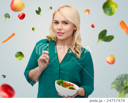 smiling young woman eating vegetable salad smiling young woman eating vegetable salad 24757479