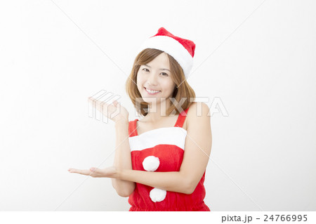女性　クリスマス　サンタクロース衣装　バストアップ　室内　両手　手差し　おすすめ　指し示す　白壁 24766995
