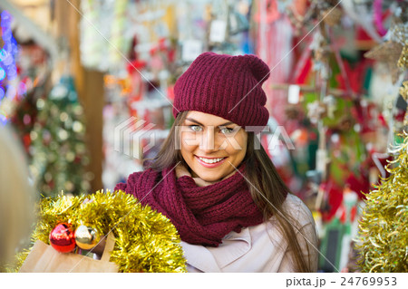 Cheerful smiling woman choosing Christmas decoration Cheerful smiling woman choosing Christmas decoration 24769953
