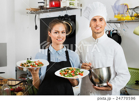 Smiling cook giving to waitress ready to serve salad 24770596