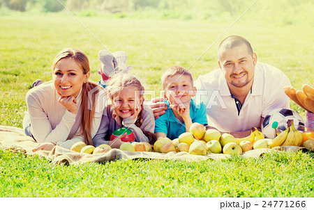 Happy mother and father with two teenagers lying in the garden Happy mother and father with two teenagers lying in the garden 24771266