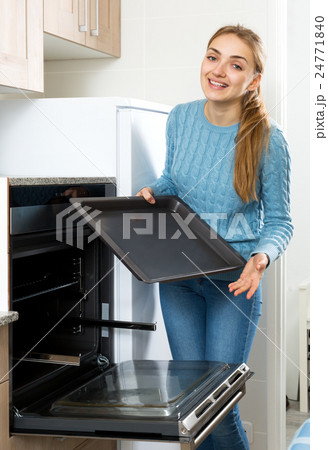 Woman placing roasting tray in kitchen oven Woman placing roasting tray in kitchen oven 24771840
