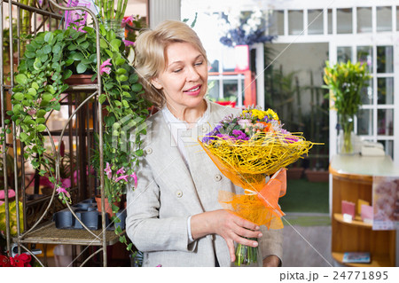 Cheerful mature blond woman selecting flowers 24771895