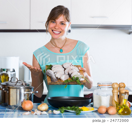 Woman with fish and frying pan at kitchen. 24772000