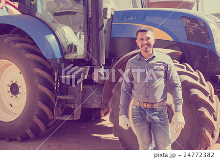 Happy driver farmer standing with big tractor Happy driver farmer standing with big tractor 24772382