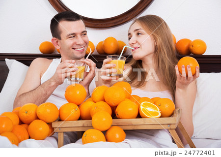 Young cheerful smiling couple with ripe oranges Young cheerful smiling couple with ripe oranges 24772401