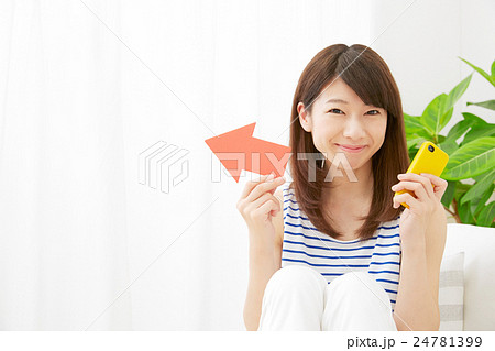 女性 矢印指し スマホ持ち リビング 女性 矢印指し スマホ持ち リビング 24781399