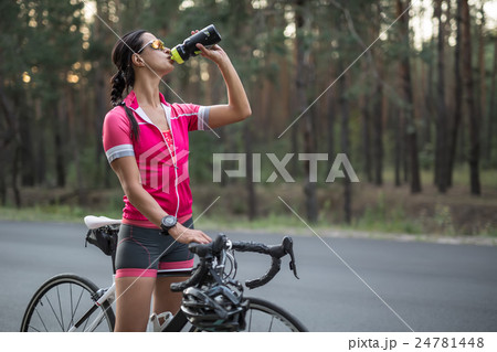 Girl with bike drinks from flask 24781448