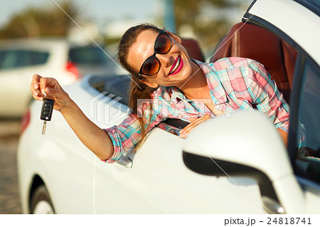 Woman sitting in a convertible car with the keys 24818741