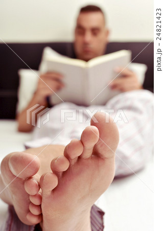 young man reading a book in bed 24821423