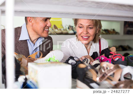 Mature couple picking shoes in boutique. Mature couple picking shoes in boutique. 24827277