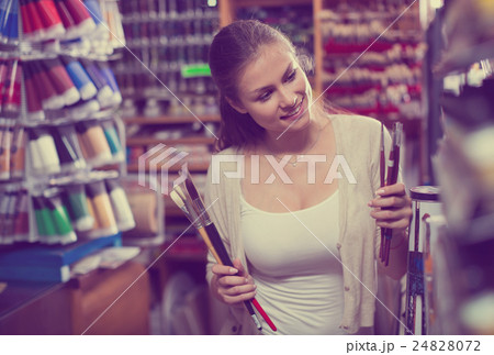 young woman selecting brushes in shop 24828072