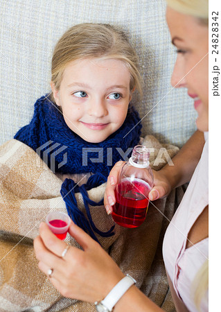 Stressed woman giving liquid medicine to little girl with grippe 24828342
