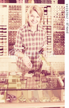 woman seller standing at counter with various scissors in sewing store 24828344