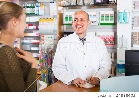 Pharmacist serving client in pharmacy . Pharmacist serving client in pharmacy . 24828403