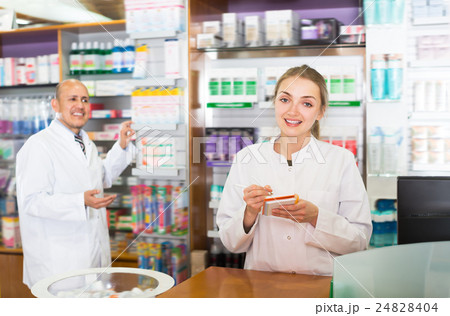 Young pharmacist and pharmacy assistant helping Young pharmacist and pharmacy assistant helping 24828404