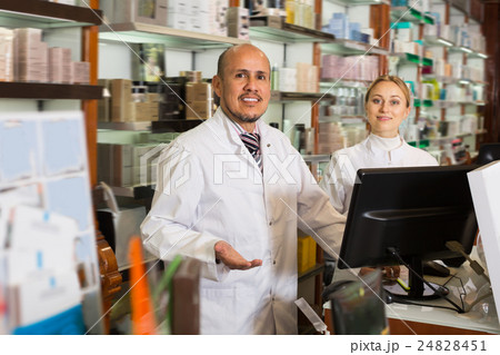 Two pharmacists standing next to shelves Two pharmacists standing next to shelves 24828451
