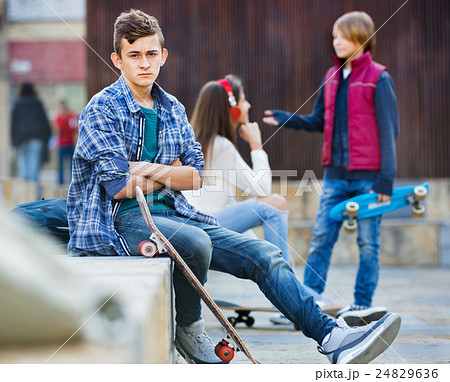Offended boy and couple of teens apart on the street 24829636