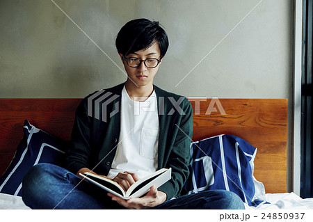 ベッドで本を読む男性の写真素材