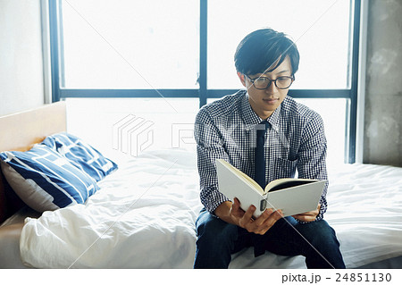 ベッドに腰掛けて本を読む男性の写真素材 24851130 Pixta
