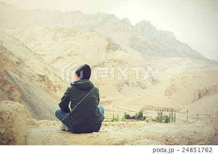 Young male traveler sitting on cliff, thinking Young male traveler sitting on cliff, thinking 24851762