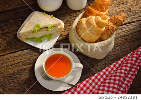 Cup of tea with sandwich and croissant on wooden Cup of tea with sandwich and croissant on wooden 24852381