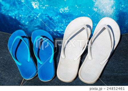 Beach slippers on border of swimming pool Beach slippers on border of swimming pool 24852461